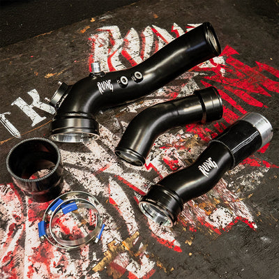High-performance BMW M2 N55 Charge Boost Pipe Kit by RVNG with black aluminum piping, clamps, and silicone connectors on a rugged surface.